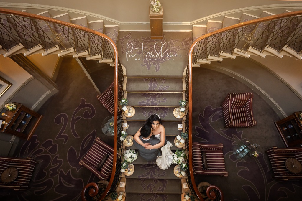 Luxury Indian wedding couple portrait shot from above on an ornate sweeping staircase